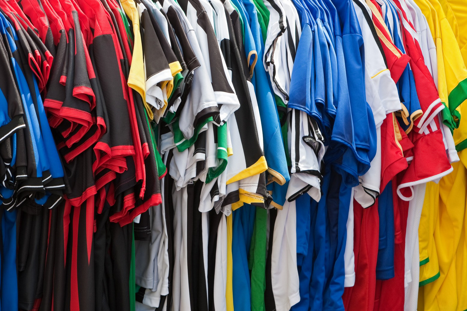 many different types of clothing are hanging on a rack